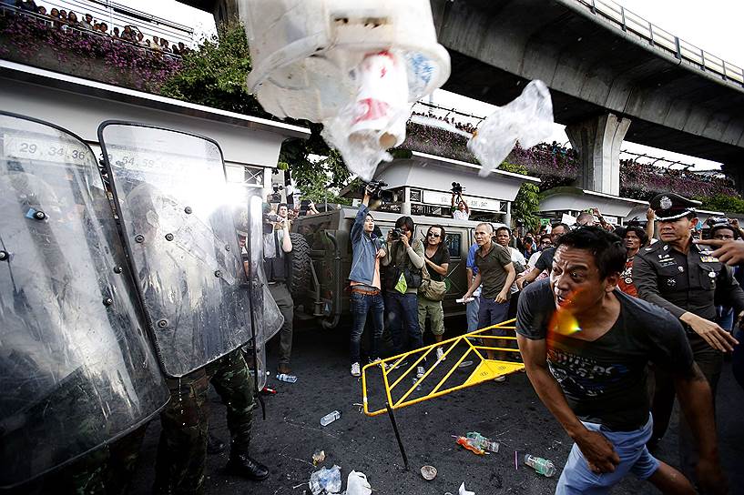 Демонстрант кидает мусорный бак в солдат во время акции протеста в Бангкоке против военного переворота в стране