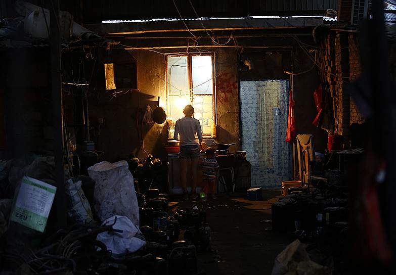 Женщина готовит еду в доме рабочих, занятых переработкой электронного мусора, в деревне Дунсяокоу на окраине Пекина