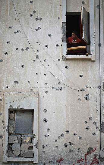 Палестинский ребенок смотрит из окна своего дома в Хан-Юнисе на юге Сектора Газа