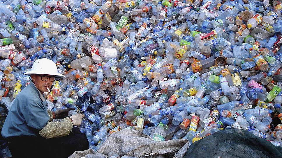 Работник собирает пластиковые бутылки на свалке мусора в Хуайбэе в Китае