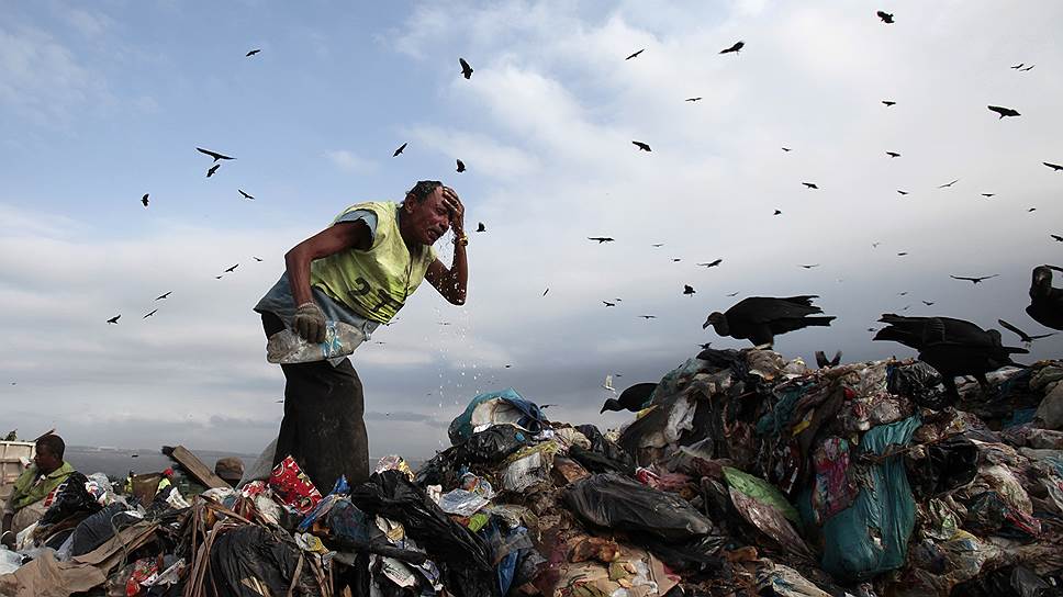Рабочий собирает перерабатываемые материалы на свалке в Рио-де-Жанейро, Бразилия