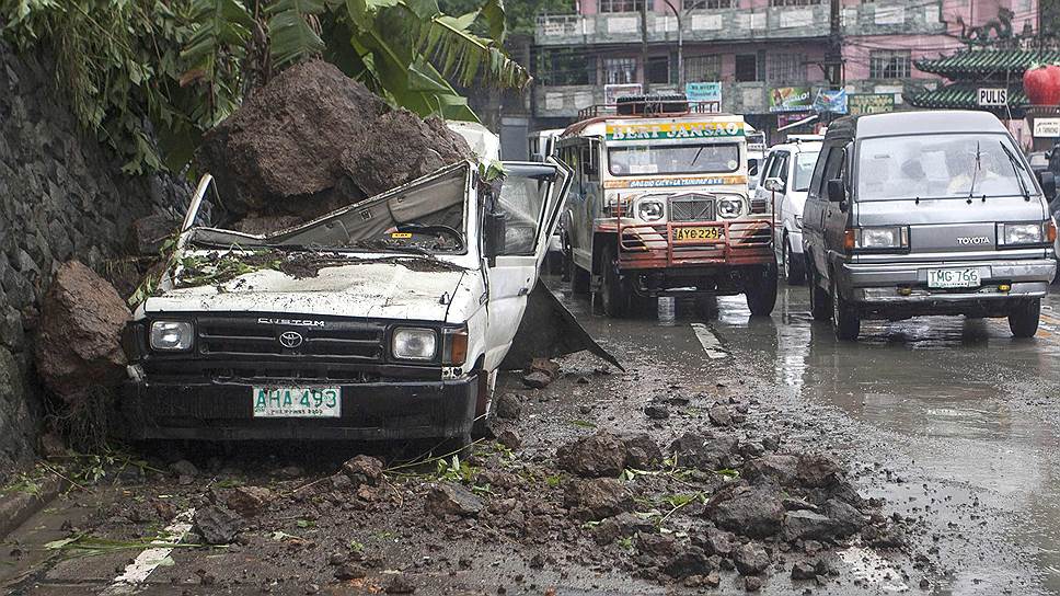 Машины проезжают мимо автомобиля, поврежденного в результате оползня (который был спровоцирован тайфуном Эстер), в горном курортном городе Багио (северные Филиппины)