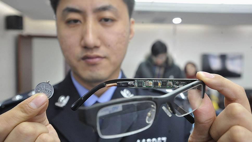 Полицейский демонстрирует очки с вмонтированной в них видеокамерой и микрофоном, конфискованные полицией и предназначенные для мошенничества во время государственных вступительных экзаменов в колледж в провинции Ляонин, Китай