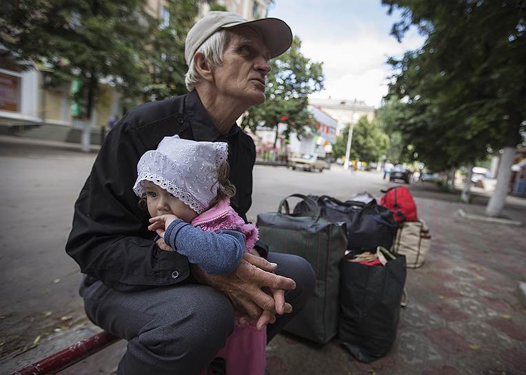 68-летний житель Славянска Виктор с внучкой Алисой в ожидании автобуса, который вывезет их из города, находящегося в зоне боевых действий