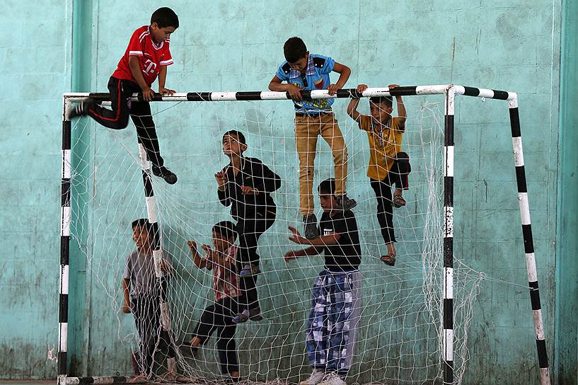 Юные беженцы из Сирии и Палестины играют на футбольном поле в лагере беженцев Аль-Бакаа недалеко от Аммана, Иордания