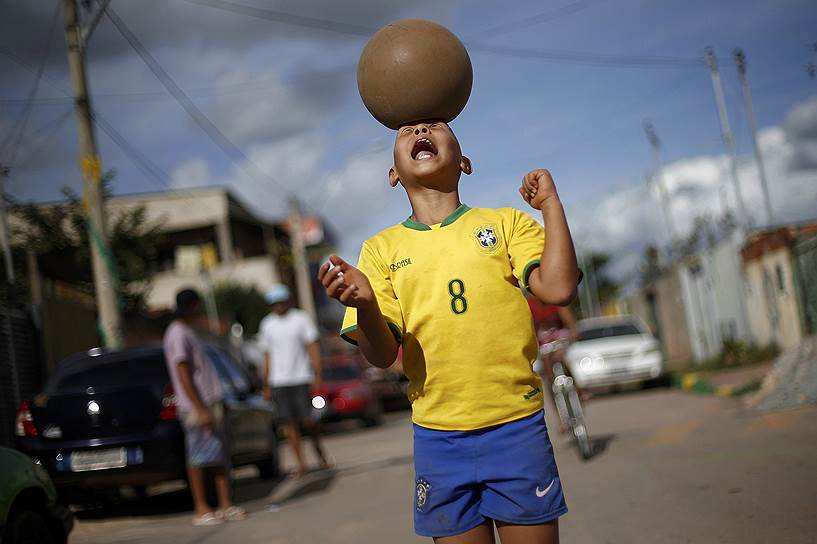 Ребенок играет с мячом на улице в фавеле Вархо на окраине Бразилиа