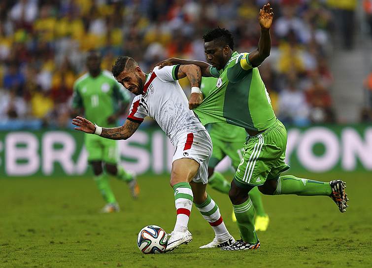 Борьба за мяч между футболистами сборной Ирана Ашканом Дежага (слева) и сборной Нигерии Джозефом Йобо
