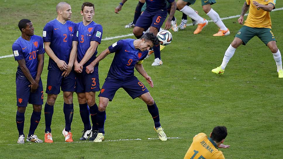 Робин Ван Перси (номер 9) из сборной Нидерландов отбивает мяч, посланный футболистом сборной Австралии Миле Единаком (номер 15)