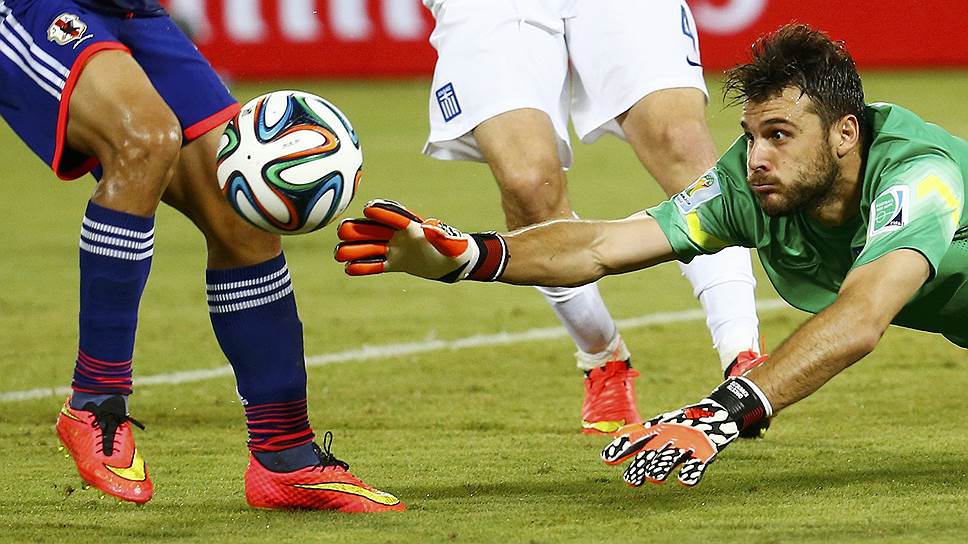 Футболист сборной Греции Орестис Карнезис ныряет за мячом во время матча со сборной Японии