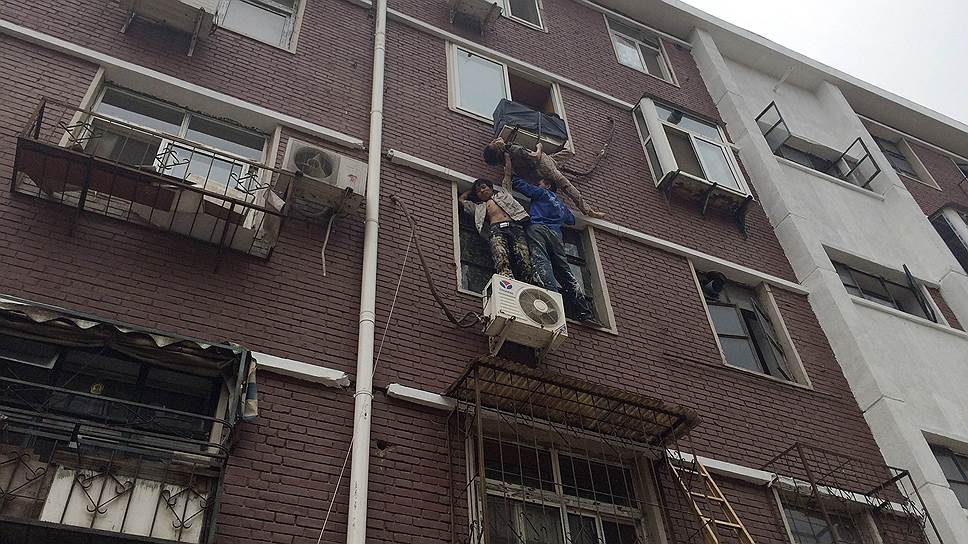 Жители китайского Тяньцзиня держат пожилую женщину, выпавшую из окна своей квартиры и зацепившуюся за стойку кондиционера на стене дома. Трое мужчин (один поддерживал женщину с помощью веревки из квартиры) держали свою соседку до прибытия пожарных