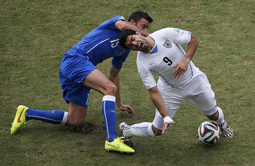 Футболист из Уругвая Луис Суарес (справа) сражается за мяч с итальянцем Андреа Бардзальи