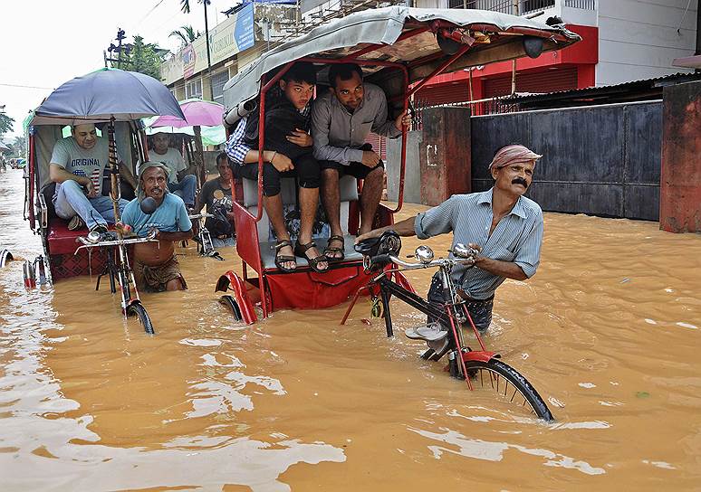 Работа рикш во время наводнения в Гувахати в индийском штате Ассам