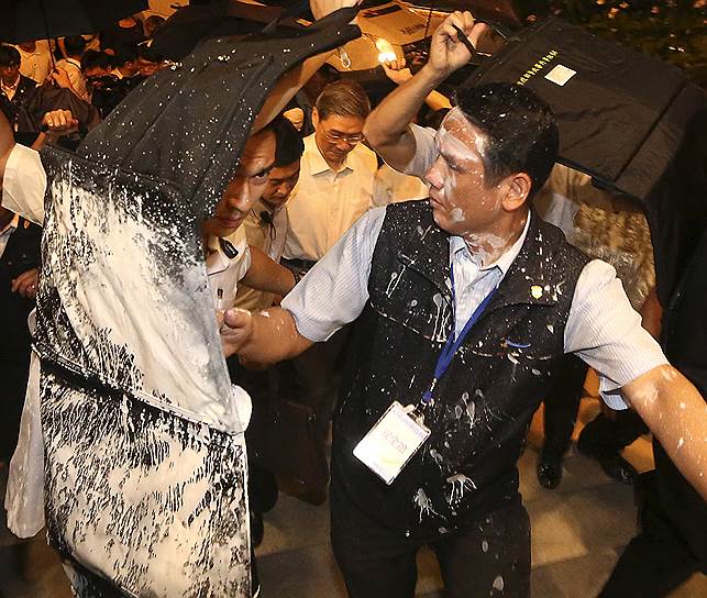 Телохранители защищают китайского министра по делам Тайваня Чжана Чжиуна от протестующих, пытающихся облить его белой краской в Гаосюне на юге Тайваня