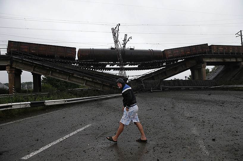 Мужчина идет мимо разрушенного железнодорожного моста в районе села Новобахмутовка, Донецкая область, Украина