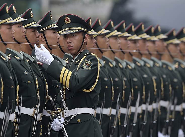 Офицер китайской Народно-освободительной армии использует струну, чтобы убедиться, что члены почетного караула выстроились в прямую линию перед церемонией встречи канцлера Германии Ангелы Меркель