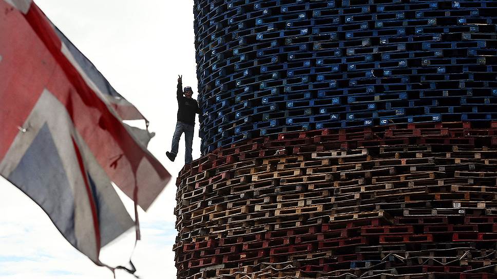 Мужчина на вершине костра, который будет зажжен 11 июля в преддверии торжеств, проводимых членами Ордена оранжистов в западном Белфасте, Северная Ирландия
