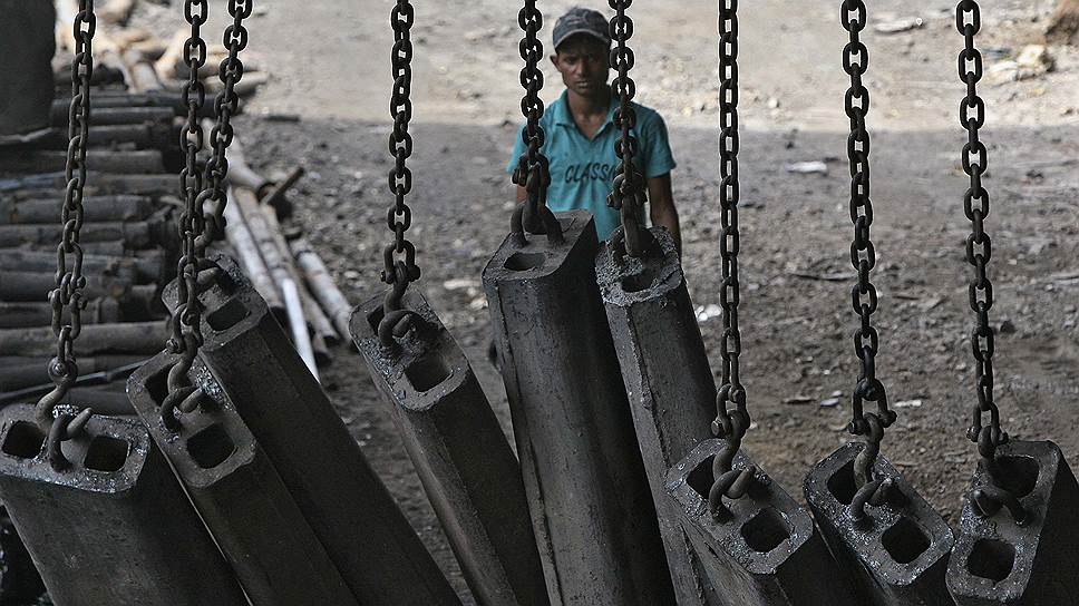 Рабочий готовится разгружать стальные кирпичи на сталелитейном заводе на окраине Джамму, Индия