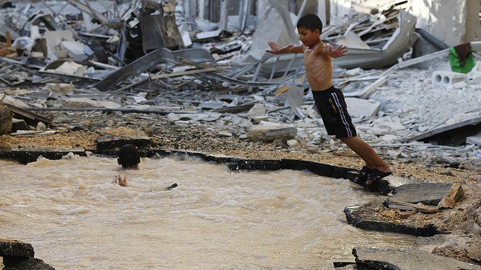Мальчик ныряет в заполненную водой яму, образовавшуюся от падения бомбы, в Алеппо, Сирия