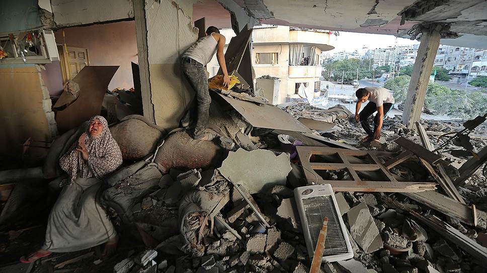 В Секторе Газа палестинская женщина плачет среди развалин своего дома, который, по заявлению местных властей, пострадал во время израильского авианалета