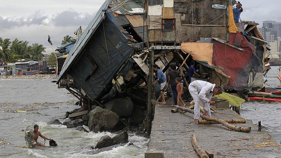 Люди работают вокруг дома, разрушенного тайфуном Гленда (по международной классификации — Рамассун). Тайфун пронесся по территории Филиппин, погибли 38 человек