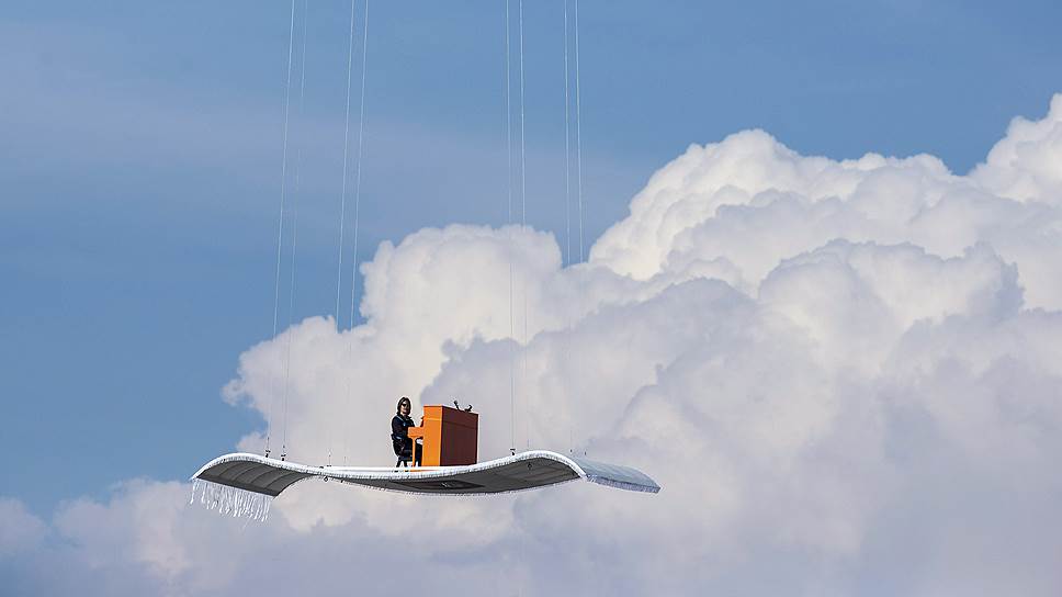 Немецкий пианист Штефан Аарон играет на оранжевом пианино на «ковре-самолете», подвешенном к вертолету над аэропортом в Мюнхене