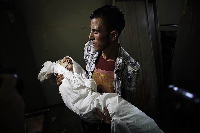 Палестинец держит тело двухлетней девочки, погибшей во время израильского обстрела в Бейт-Лахии, сектор Газа