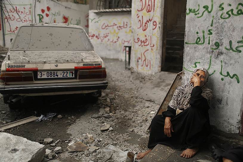 Палестинская женщина смотрит на дома, разрушенные во время израильского авиаудара на севере сектора Газа