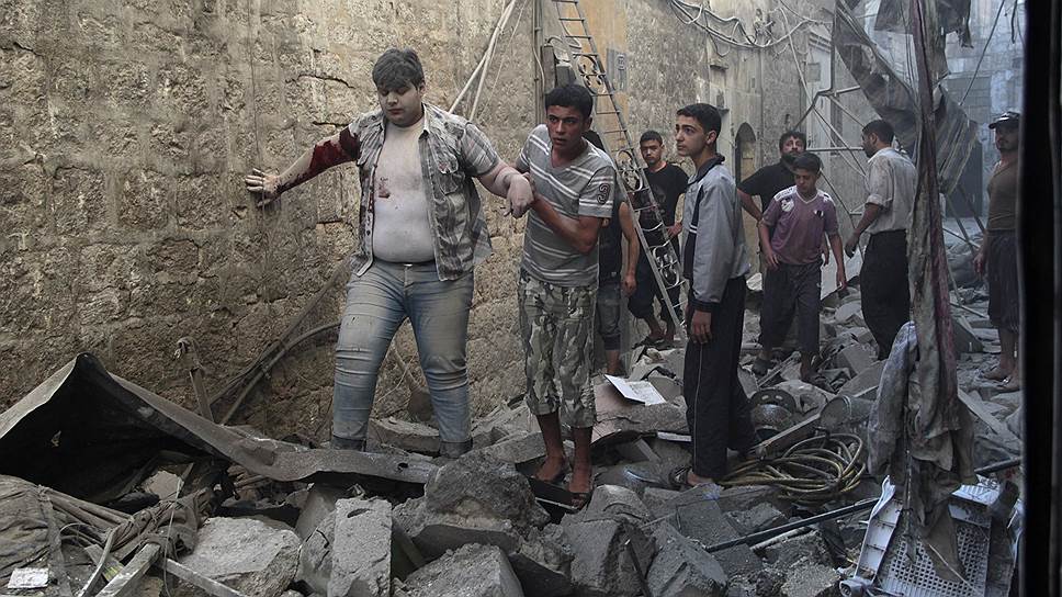 Жители Алеппо помогают мужчине,раненному во время авиаудара сил, лояльных Башару Асаду