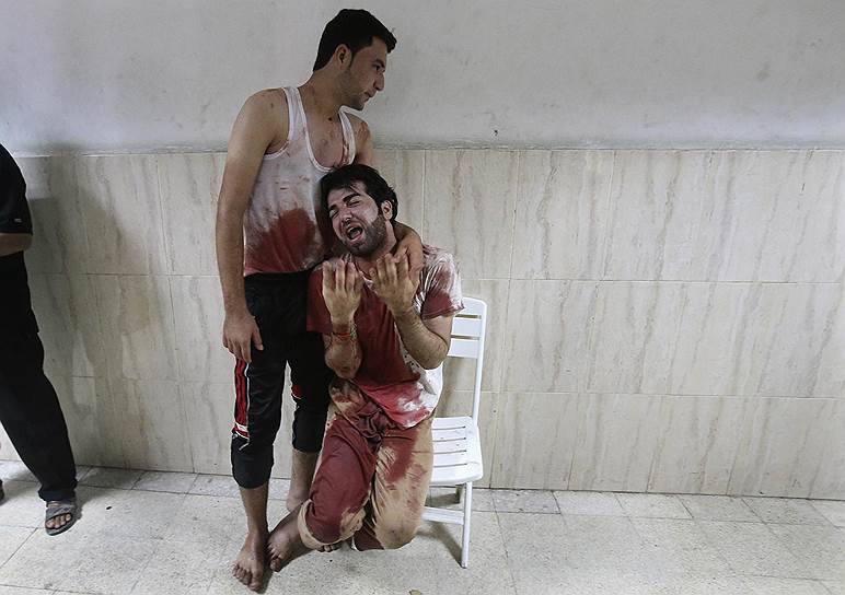 23.07.14. Палестинский мужчина утешает друга, отец которого был убит во время обстрела