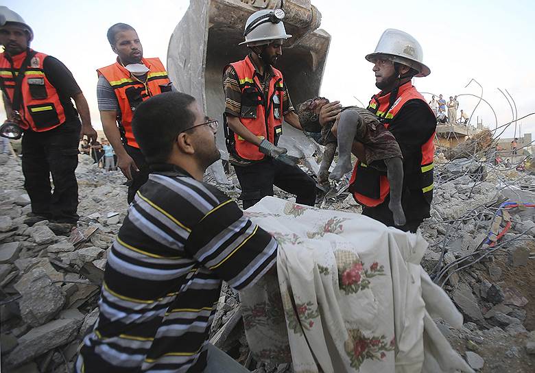 26.07.14. Палестинские спасатели на руинах дома в Хан-Юнисе