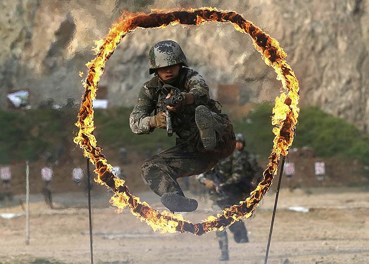 Китайский военнослужащий прыгает через горящее препятствие во время тренировки к Дню Армии на военной базе в Циндао