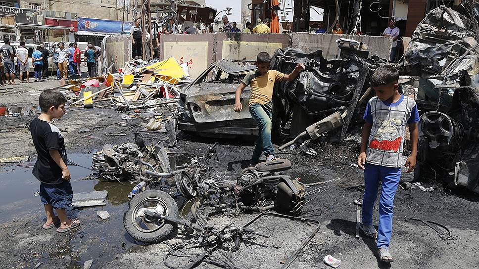 Дети в Багдаде смотрят на взорванный бомбой автомобиль