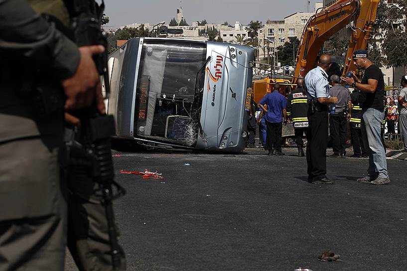 Израильские полицейские стоят у перевернутого автобуса после предполагаемой атаки палестинцев на Иерусалим