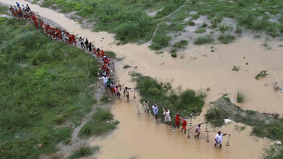 Последователи бога Шивы несут горшки, наполненные водой из реки Ганг, в городе Аллахабад на севере Индии