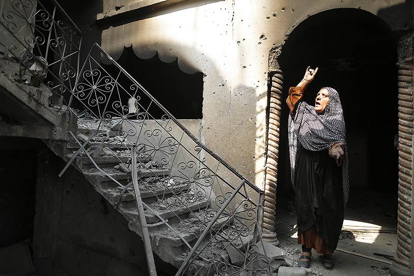 Палестинская женщина рядом с ее домом в Бейт-Ханун на северо-востоке Сектора Газа, разрушенным во время обстрела