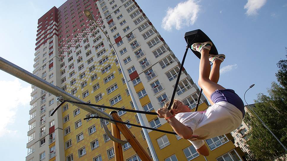 Девочка качается на качелях у высотного жилого дома в Нижнем Новгороде