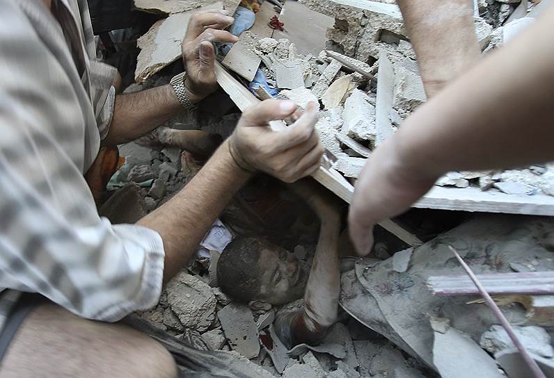 Палестинцы достают мальчика из-под обломков дома, разрушенного во время израильской воздушной атаки