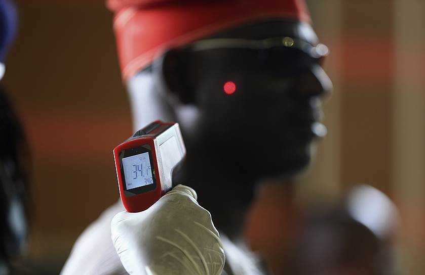 Измерение температуры тела с помощью лазерного термометра в аэропорту Абуджи, Нигерия