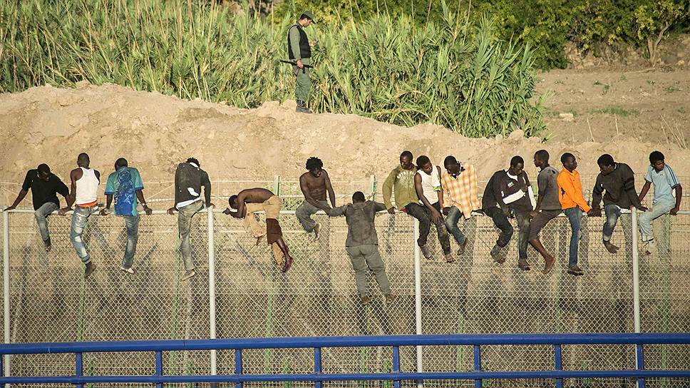 Африканские мигранты перелезают стену, отделяющую Марокко от Мелильи, в попытке пробраться на территорию Европы