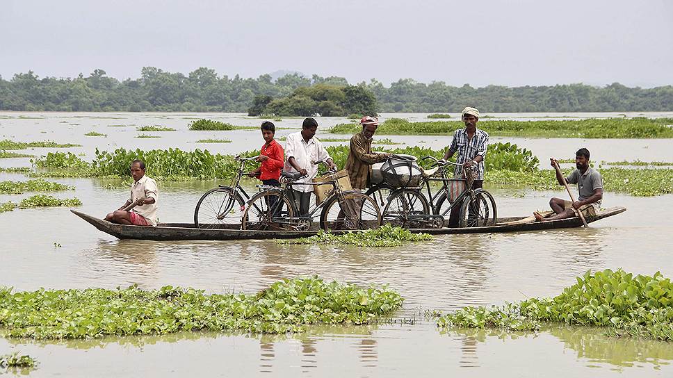 Местные жители перевозят велосипеды в одном из затопленных регионов индийского штата Ассам