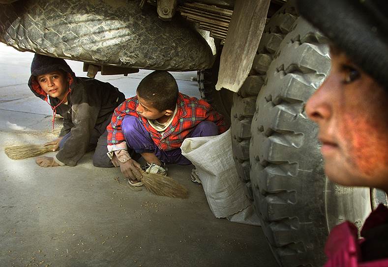 2001 год. Афганские дети собирают просыпавшееся зерно из-под грузовика с гуманитарной помощью