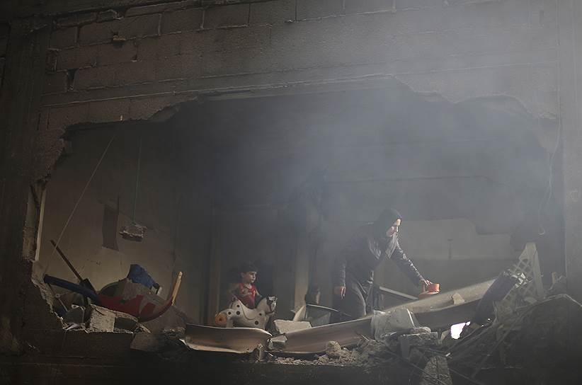 Палестинская женщина осматривает свой дом в Рафахе, поврежденный во время атаки израильских военных