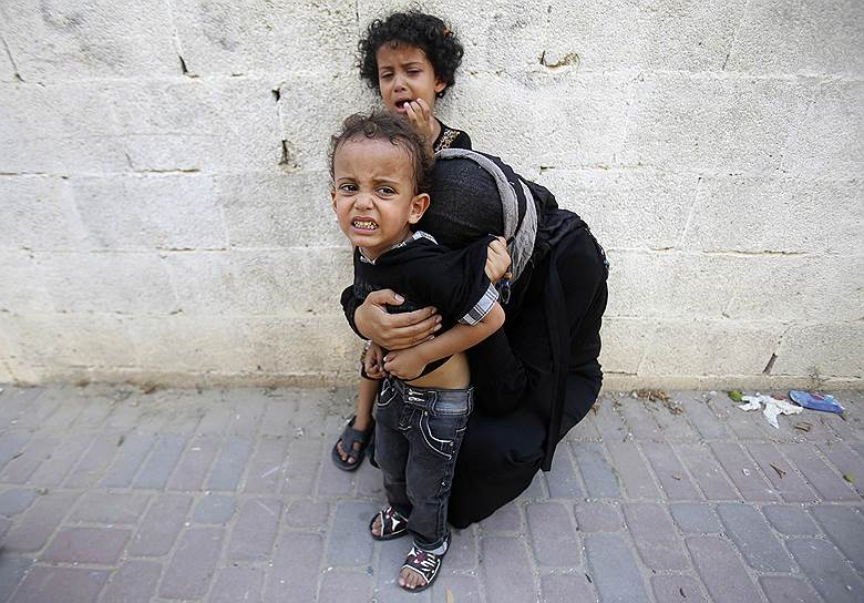 Палестинка с детьми скорбит о гибели своих родных, погибших, по словам свидетелей, во время израильского воздушного удара по сектору Газа