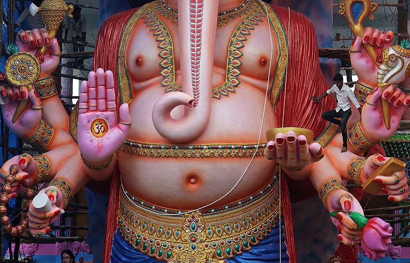 Индиец взбирается на 18-метровую статую индуистского бога Ганеши, чтобы украсить ее по случаю приближающегося фестиваля, посвященного этому божеству (Хайдарабад, Индия)