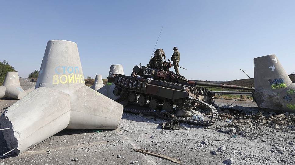 Украинские солдаты осматривают подбитый танк на окраине Мариуполя