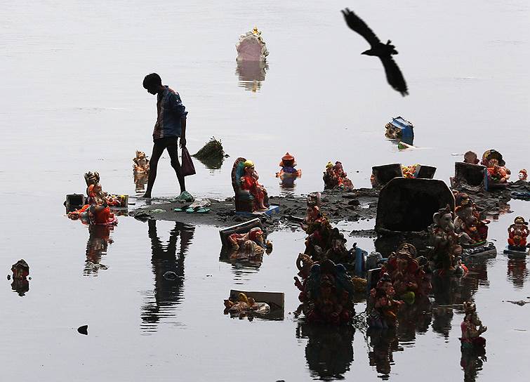 Мальчик собирает брошенные в воду фигурки бога Ганеши в Индии