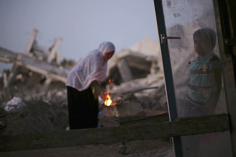 Палестинская женщина готовит кофе на огне рядом с развалинами своего дома