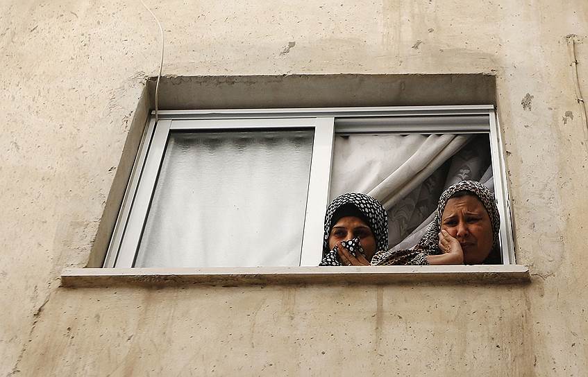 Женщины смотрят из окна на похоронную процессию палестинца, убитого израильскими солдатами, в Рамаллахе, Западный берег реки Иордан