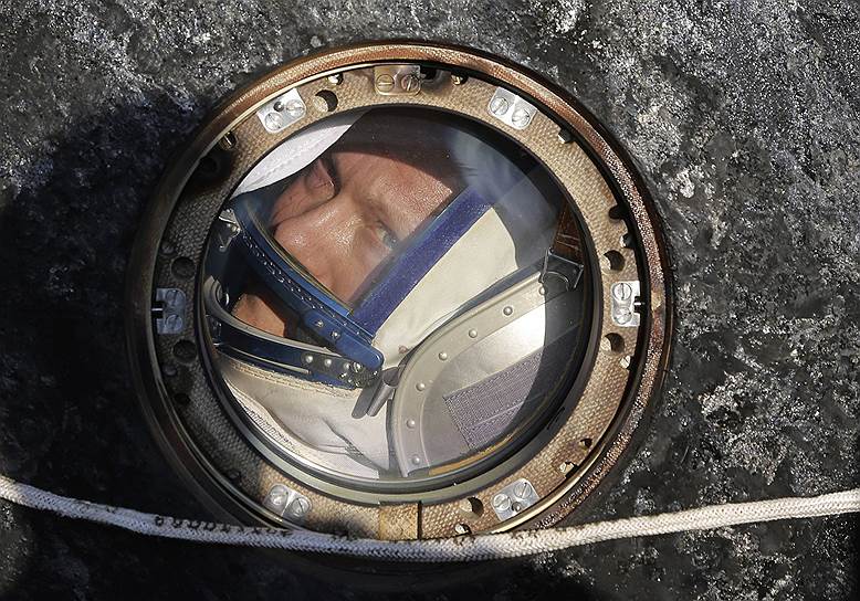 Космонавт Олег Артемьев выглядывает из иллюминатора спускаемой капсулы Союз ТМА-12М после посадки в Казахстане