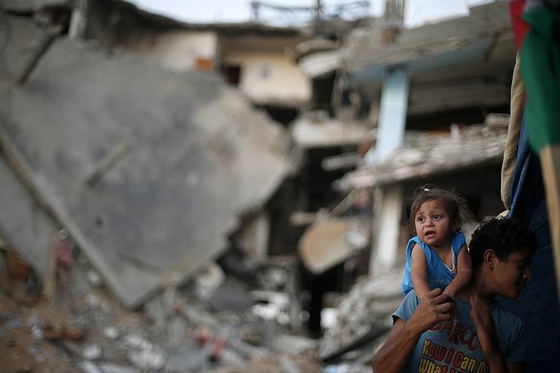 Палестинский мальчик с сестрой возле руин дома в Газе